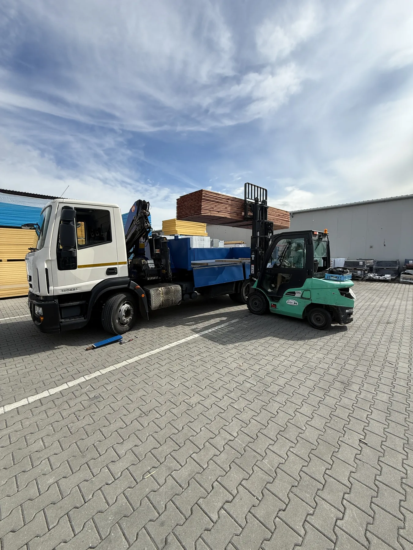 Vlastní Iveco Kontejnerovka.cz při nakládce stavebního materiálu vysokozdvižným vozíkem