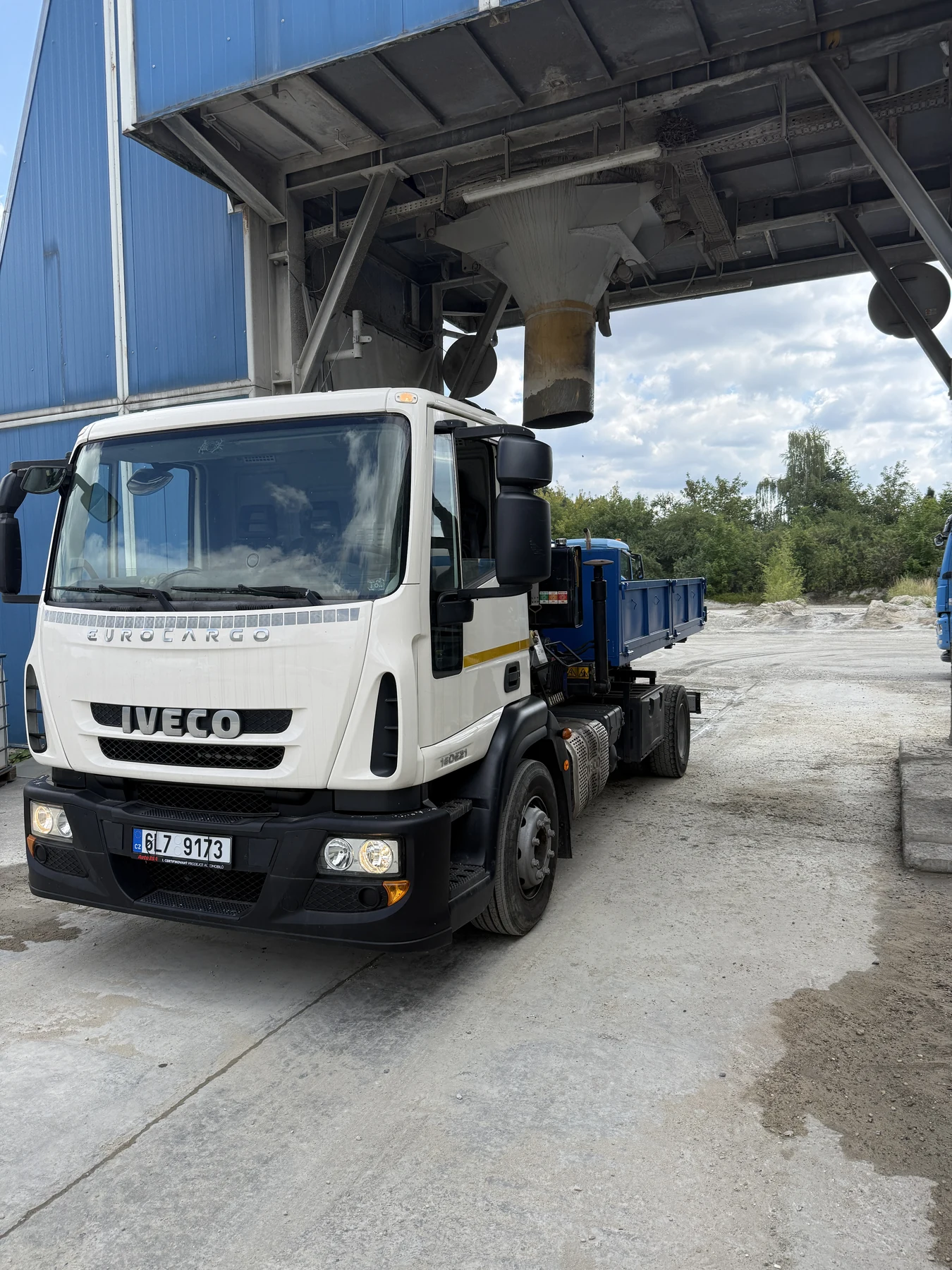 Vlastní Iveco Kontejnerovka.cz při nakládce sypkého materiálu pod zásobníkem
